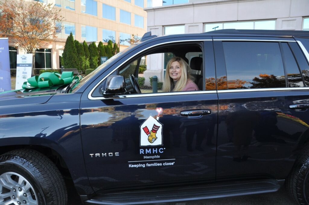 woman in the driver's seat of a Chevy Tahoe with the RMHC logo on the door