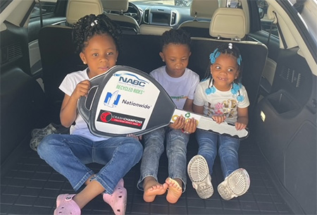 Corina Kelley's three children sitting in their new NABC Recycled Rides vehicle
