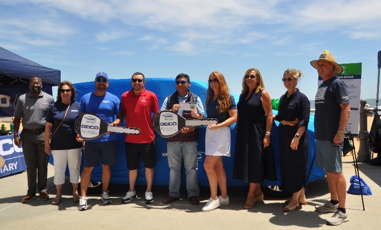 Victor Espinoza and his family standing with his blanketed NABC Recycled Rides vehicle